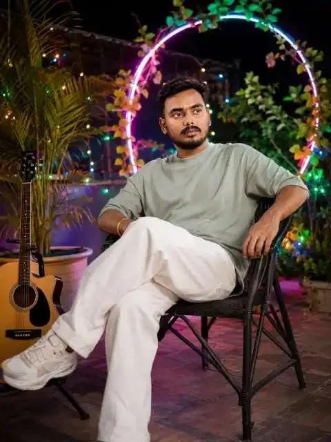 नाइट आउटडोर गोल्डन विजुअल के साथ नाइट आउटडोर गोल्डन डेकोरेटेड लोकेशन पर लड़का बैठा हुआ है